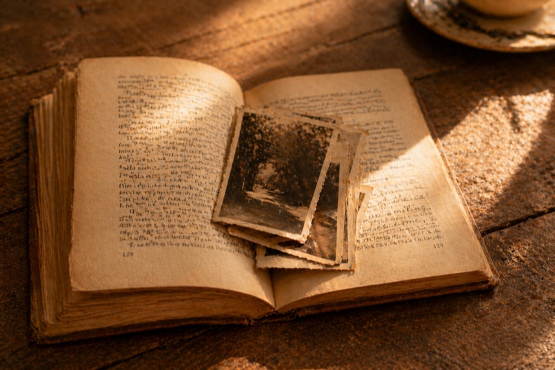 An old book open to a page with vintage photographs tucked between the pages